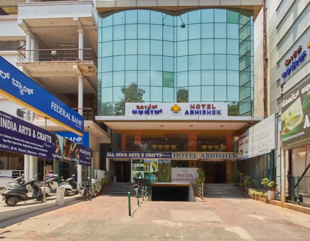 A building complex with signs for "Hotel Abhishek" and "Federal Bank." The hotel has a modern, glass-fronted design. The image could be used by Aspire Digital Solutions to demonstrate their marketing services for a hospitality business.