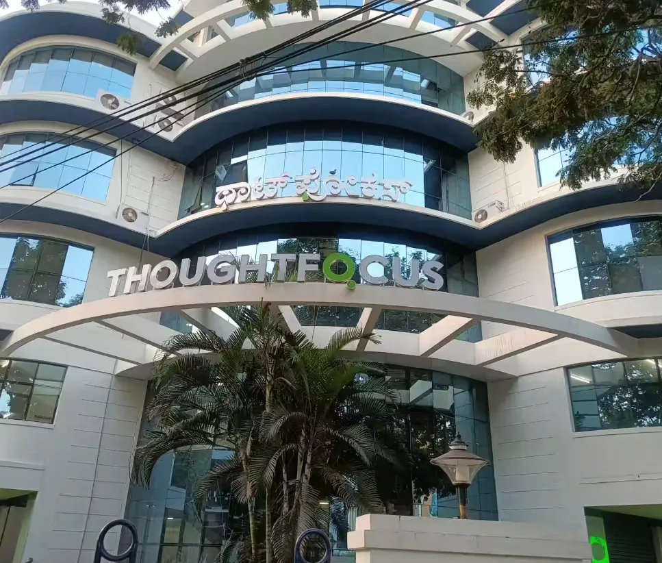 A professional photo of the "ThoughtFocus" office building, with its name clearly visible on the modern glass facade. This image is an excellent example of a corporate office. It could be used by Aspire Digital Solutions to showcase their services for a tech company or similar business.